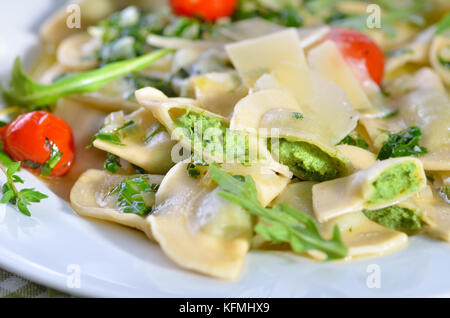 Nudeln gefüllt mit Spinat und Quark (Südtiroler Spezialität so chlutzkrapfen" genannt) mit Ruccola butter Soße und Cocktail Tomaten serviert. Stockfoto