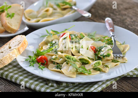 Nudeln gefüllt mit Spinat und Quark (Südtiroler Spezialität so genannte chlutzkrapfen') mit Ruccola butter Soße und Cocktail Tomaten serviert. Stockfoto