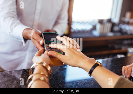 Frau Zahlung mit Kreditkarte im Cafe. Fokus auf Frau Hände Eingabe sicherheits-pin in Credit card reader. Stockfoto