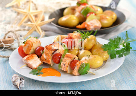 Gebratener Lachs Spieße mit Obst und Gemüse Bratkartoffeln mit Rosmarin, ein Pan im Hintergrund Stockfoto