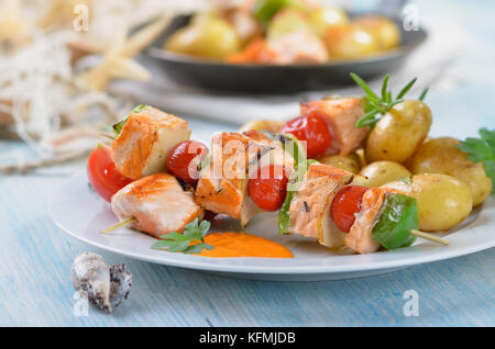 Gebratener Lachs Spieße mit Obst und Gemüse Bratkartoffeln mit Rosmarin, ein Pan im Hintergrund Stockfoto