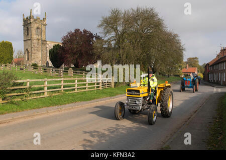 Mann, der alten gelben vintage MF-Traktor durch Bugthorpe Dorf auf Wolds Vintage Gruppe Straße laufen, eine jährliche Charity Event - Yorkshire, England, UK. Stockfoto