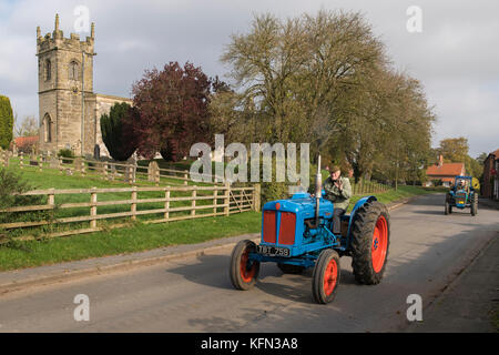Mann, der alten blauen Oldtimer Traktor durch Dorf Bugthorpe auf Wolds Vintage Gruppe Straße laufen, eine jährliche Charity Event - Yorkshire, England, UK. Stockfoto