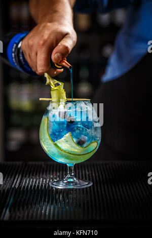 Barkeeper Vorbereitung einer Blue Gin Tonic mit Curacao Stockfoto