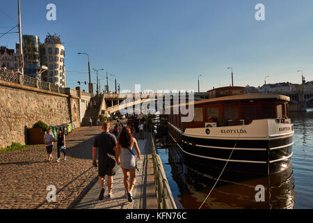 Menschen flanieren Sie entlang der Moldau in Prag, Tschechien direkt unter dem Tanzenden Haus von Frank Gehry entworfenen Stockfoto