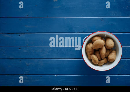 Kartoffeln in ein weißes Sieb auf blauen Tabelle Stockfoto