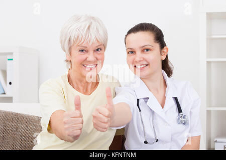 Glückliche junge Arzt und Patient zeigen Daumen anmelden Stockfoto