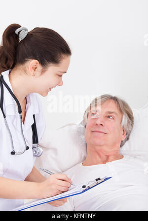 Ältere männliche Patienten, Arzt schriftlich über die Zwischenablage Stockfoto