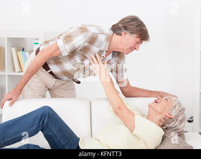 Reife Frau auf Sofa, während Mann hinter der Couch stand Stockfoto