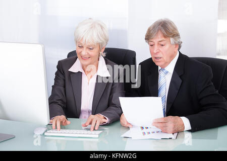 Reifen Sie, Geschäftsmann und Geschäftsfrau Blick auf Computer Stockfoto