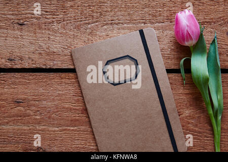 Retro Notebook und einem Tulip Frühling Atmosphäre auf hölzernen Schreibtisch Stockfoto