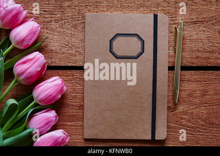 Notebook und Feder Feder Atmosphäre mit rosa Tulpen Stockfoto