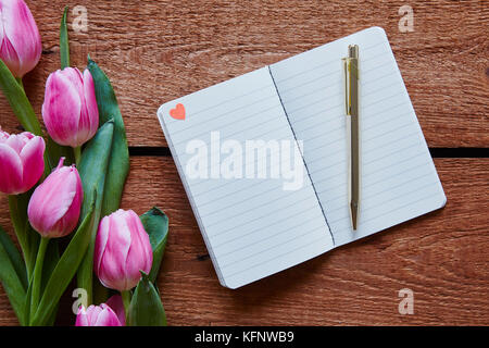Notebook mit kleinen Herzen Tulpen im lebhaften Atmosphäre Stockfoto
