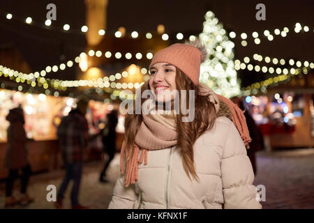 Glückliche junge Frau am Weihnachtsmarkt im Winter Stockfoto