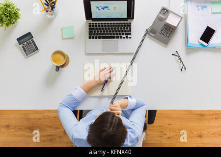 Geschäftsfrau fordert Telefon am Schreibtisch Stockfoto