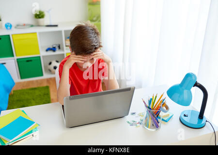 Müde Schüler Junge mit Laptop Computer zu Hause. Stockfoto