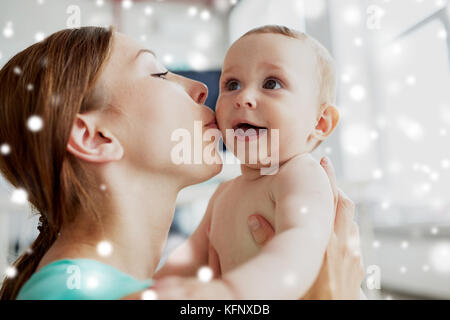 Glückliche junge Mutter küssen kleines Baby zu Hause Stockfoto