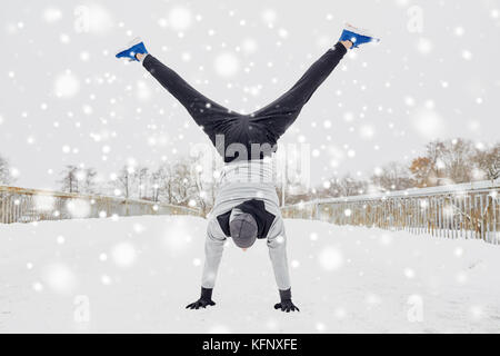 Junger Mann macht Handstand im Winter Stockfoto
