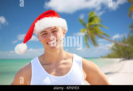 Glückliche junge Mann in Santa Hut am Strand zu Weihnachten Stockfoto