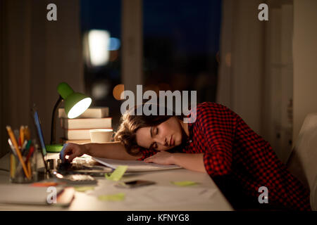 Student oder Frau schlafen auf Tisch bei Nacht home Stockfoto