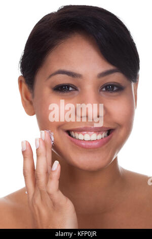 Junge Frau, die Anwendung der Creme im Gesicht Over White Background Stockfoto