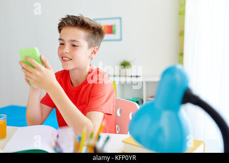 Schüler Junge mit Smartphone störende aus der Studie Stockfoto