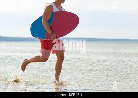 Glückliche junge Mann mit skimboard auf Sommer Strand Stockfoto