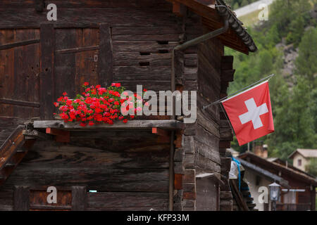 Herbriggen, Schweiz - traditionelles Gebäude aus Holz mit Blumen und Schweizer Flagge. Stockfoto