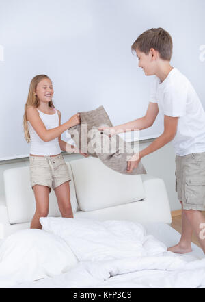 Gemeinsam kämpfen Geschwister mit einem Kissen auf dem Bett im Schlafzimmer Stockfoto