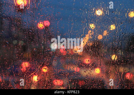 Regentropfen auf der Windschutzscheibe. Straße Verkehr abstract Licht bokeh defokussierten Licht. Hintergrund.