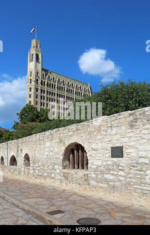 Wand des langen Baracke des Alamo Mission mit dem historischen Emily Morgan Hotel im Hintergrund in der Innenstadt von San Antonio, Texas Stockfoto