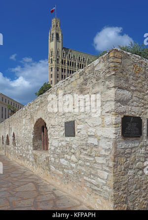 Wand des langen Baracke des Alamo Mission mit dem historischen Emily Morgan Hotel im Hintergrund in der Innenstadt von San Antonio, Texas Stockfoto