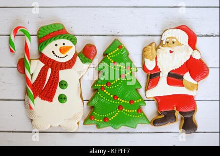 Weihnachten Neujahr Hintergrund. Lebkuchen cookies, Weihnachtsmann, Schneemann, Weihnachtsmann und Tannenbaum am weißen Tisch. nach oben anzeigen Stockfoto