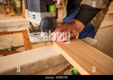 Mann, der Verarbeitung von Holz mit Router oder Maschine in eine Holzwerkstatt Stockfoto