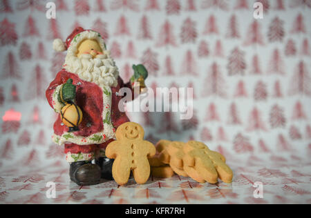 Bunte Weihnachten essen Fotografie Bild mit Rot glänzenden Weihnachtsbaum Geschenkpapier Hintergrund und Gingerbread man Kekse mit Santa Claus ornament Stockfoto