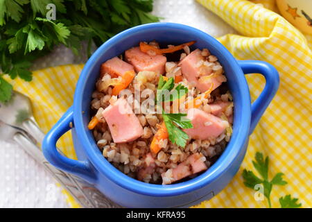 Topf mit Backofen gekocht Buchweizen und Würstchen, Zwiebeln und Möhren Stockfoto