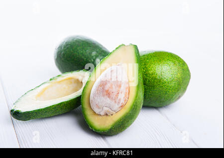 Close up Paar ganze Avocados und abgeschnittenen eins auf die weiße Holztisch. gesund leben, Ernährung, roh essen, pflanzliche Fette Konzept Hintergrund. Selektive fo Stockfoto