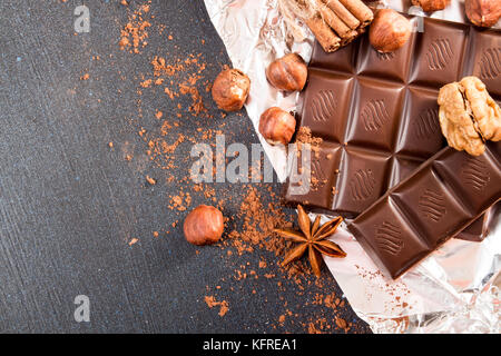 Schokolade Stücke, Haselnuß, Haselnuss, Schokolade Spänen und Walnüsse auf dunklem Hintergrund. Stockfoto