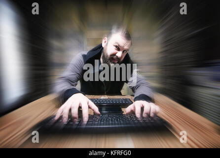 Der Hacker in der Haube sitzt und arbeitet Stockfoto