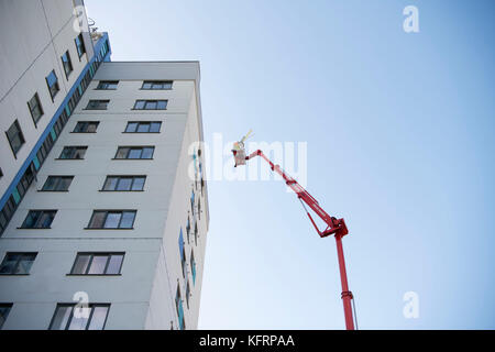 Cherry Picker erhöhten Lift neben einem Hochhaus von Gemeindewohnungen für Wartungsarbeiten in Wales, Großbritannien. Stockfoto