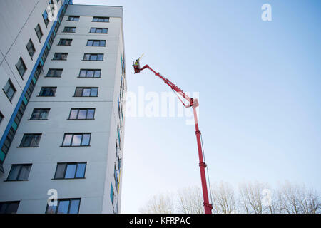 Cherry Picker erhöhten Lift neben einem Hochhaus von Gemeindewohnungen für Wartungsarbeiten in Wales, Großbritannien. Stockfoto