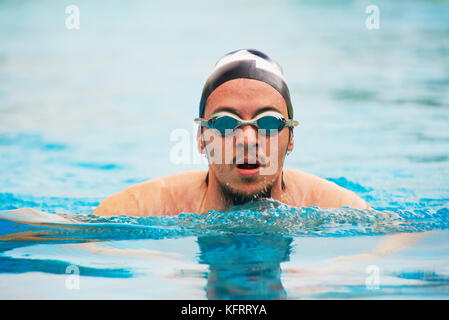 Mann in Schutzbrille schwimmen im Pool. Sportlich Mann tun schwimmen Übung Stockfoto