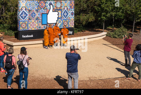 Facebook-Hauptquartier Daumen hoch Unterschreiben mit buddhistischen Mönchen und anderen Touristen fotografieren am Eingang am 1 Hacker Way In Menlo Park, Kalifornien Stockfoto