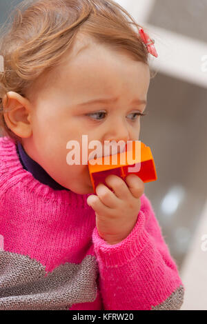 Kleinkind Baby Mädchen spielt und setzt sich in ihren Mund aus weichem Gummi Bausteine. Stockfoto