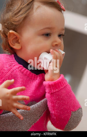 Kleinkind Baby Mädchen spielt und setzt sich in ihren Mund aus weichem Gummi Bausteine. Stockfoto