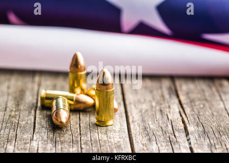 Pistolenkugel und USA-Flagge auf alten Holztisch. Stockfoto