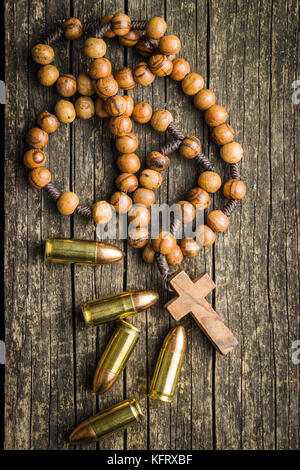 Rosenkranz und Pistole Kugeln auf alten Holztisch. Stockfoto