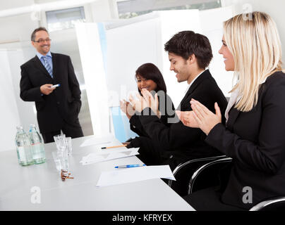 Gruppe von Geschäftsleuten bei der Präsentation Beifall klatscht an den Dozenten Stockfoto