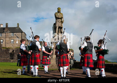 Stirling, Schottland – 17. August 2010: Piper-Band spielt vor der Statue von Robert the Bruce im Stirling Castle in Stirling, Schottland. Stockfoto