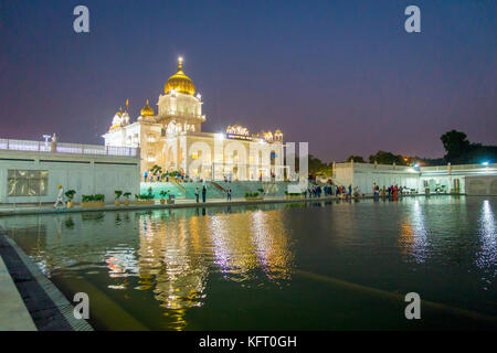 Delhi, Indien - 19. September 2017: unbekannte Menschen zu Fuß vor dem Hauptgebäude des Sikh Schreine von Delhi - Gurudwara Bangla Sahib. Das Hauptgebäude des Tempels beleuchtet ist und in sarowar Teich Wasser in Indien wider. Stockfoto